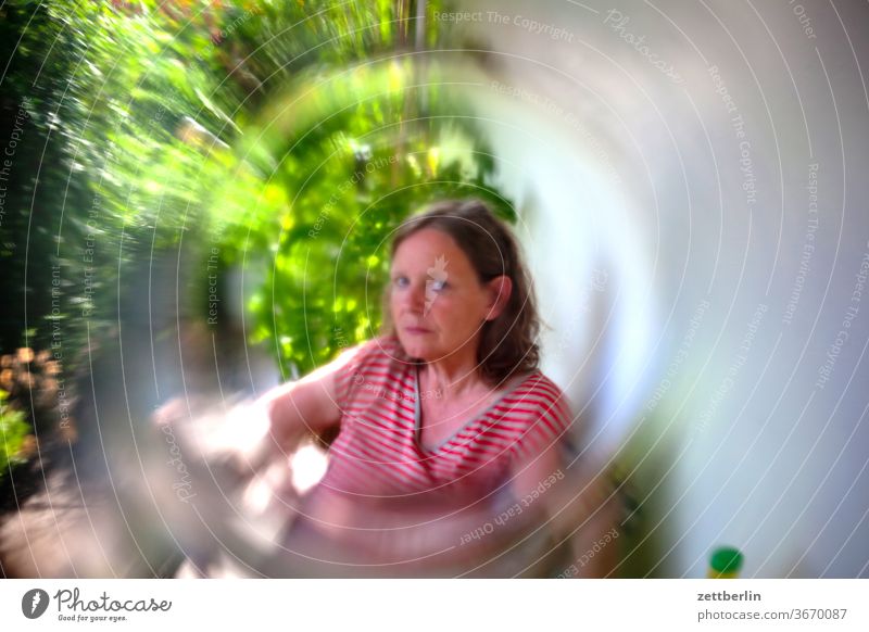 Frau, betrachtet durch ein Glas frau portrait sitzen garten ferien erholung kleingarten ferien wochenende naherholung blick blickkontakt unscharf glas linse