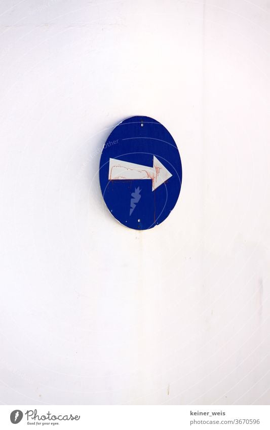 Rundes blaues Schild mit weißem Pfeil an einer weißen Wand rund rechts Richtung Weg Einbahnstraße Griechenland Südeuropa hochformat Verkehr Straßenverkehr