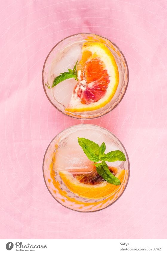 Sommerliches geeistes Zitrusgetränk mit Minze auf rosa Serviette trinken Zitrusfrüchte Wasser Cocktail Limonade aufgegossen Entzug Blutorange Kalk Frucht Saft