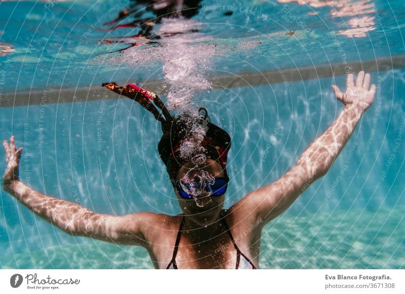 junge Frau, die in einem Schwimmbad unter Wasser taucht. Sommer und lustiger Lebensstil Sonnenbrille Schwimmsport Blasen Spaß Kaukasier Pool Sinkflug Lifestyle