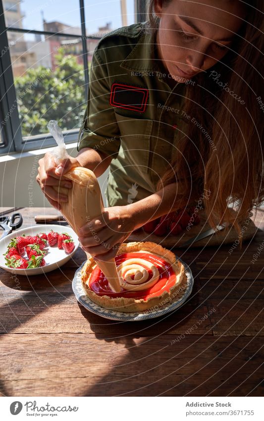 Crop Frau dekorieren Kuchen mit Sahne Spritzbeutel drücken Pasteten Koch Konditorei selbstgemacht lecker Tisch Hausfrau Lebensmittel schmackhaft heimwärts süß