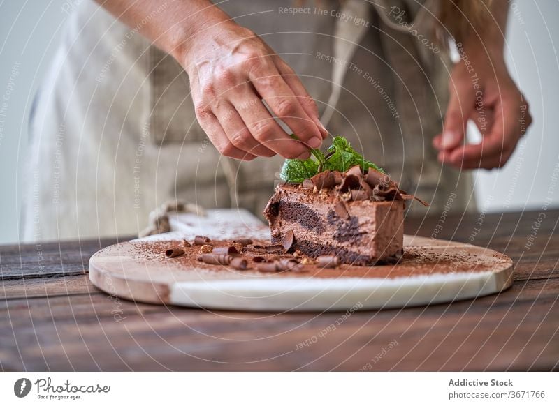 Chefkoch garniert Schokoladenkuchen mit Minze Kuchen Konditorei Frau Mousse dekorieren Garnierung machen Dessert Küche Hälfte geschnitten gebacken Sahne Koch