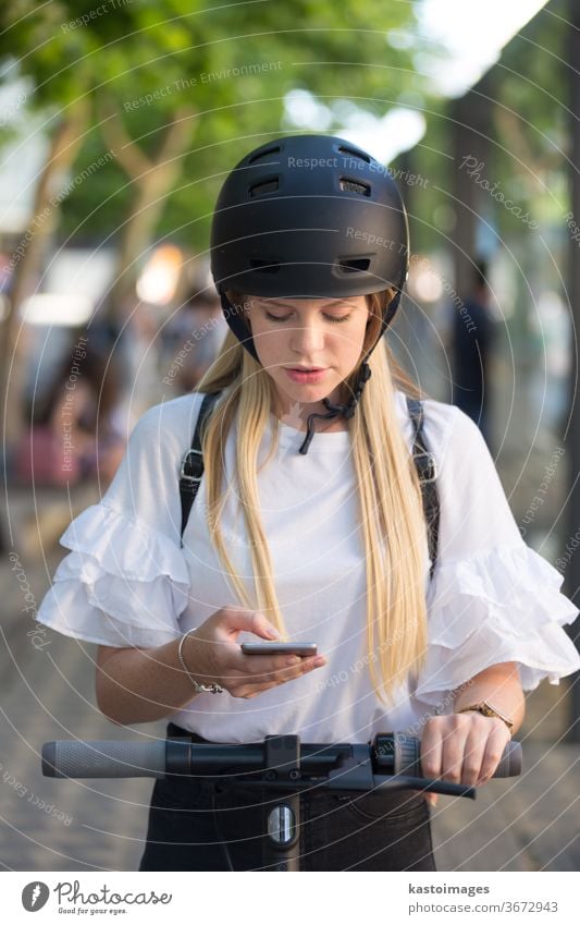 Frau, die ein Smartphone benutzt und einen modernen Elektroroller mit einer Anwendung mietet. Konzept des städtischen Verkehrs Tretroller App Fahrrad Großstadt