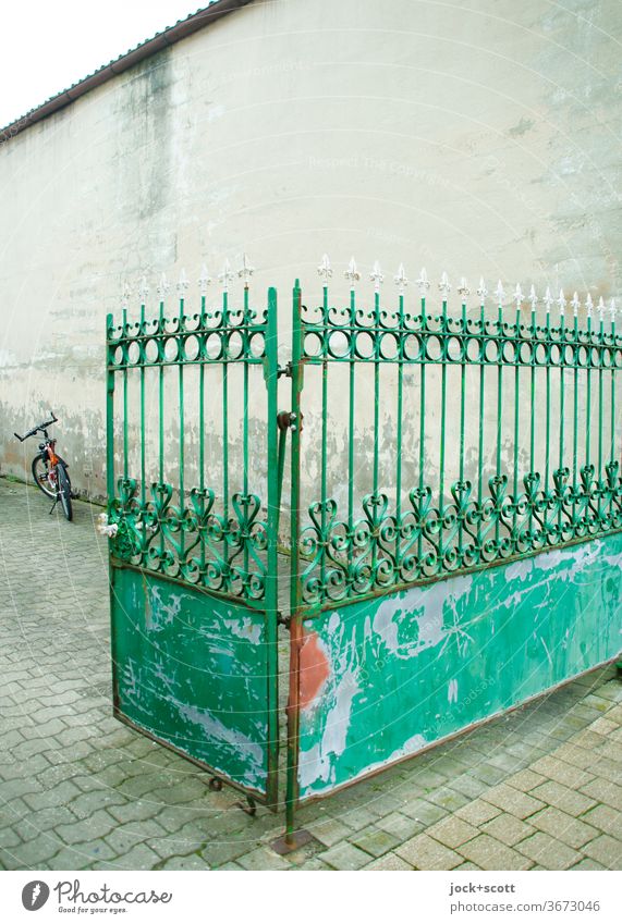 ein bewährtes Tor für die Einfahrt Zaun Fahrrad Ausfahrt alt verwittert ramponiert Wand Steinplatten Metalltor verziert Vergänglichkeit altehrwürdig offen