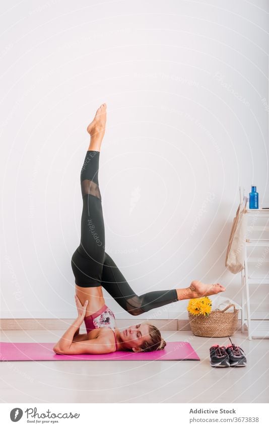 Schlanke Frau tut Salamba Sarvangasana Pose auf Yoga-Matte üben unterstützte Schulterstand-Pose Gleichgewicht Vitalität Energie Ausdauer Barfuß Unterlage