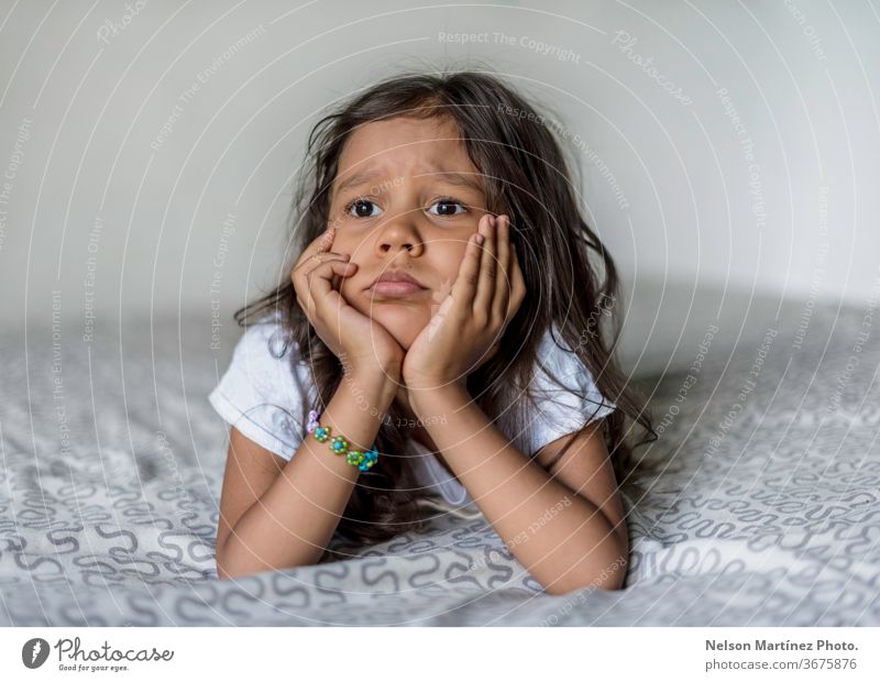 Porträt eines kleinen hispanischen Mädchens. Sie langweilt sich in ihrem Bett. Sie schaut zum Fenster. Sommer Blick wenig jung Kinder Denken Langeweile