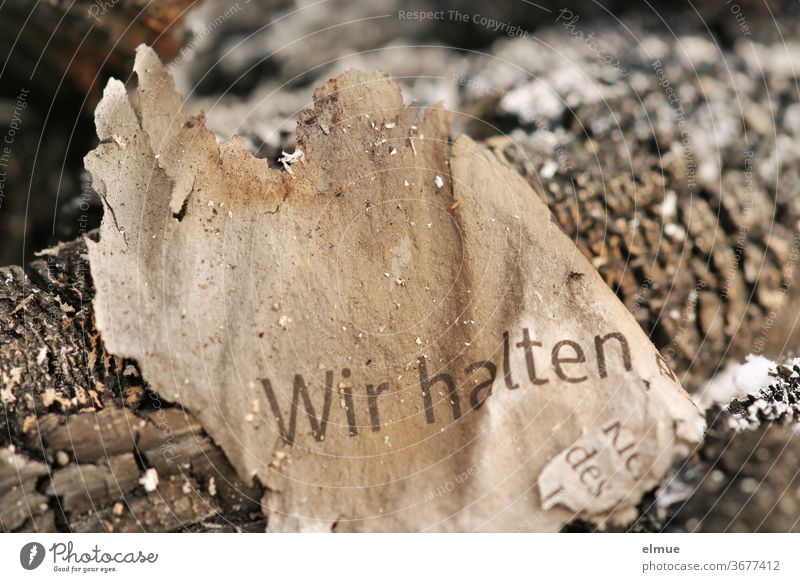 "Wir halten" steht auf dem kläglichen Rest eines angekohlten Papierschnipsels in der Asche Versprechen Holzkohle verbrannt übrig Nahaufnahme Lüge Detailaufnahme