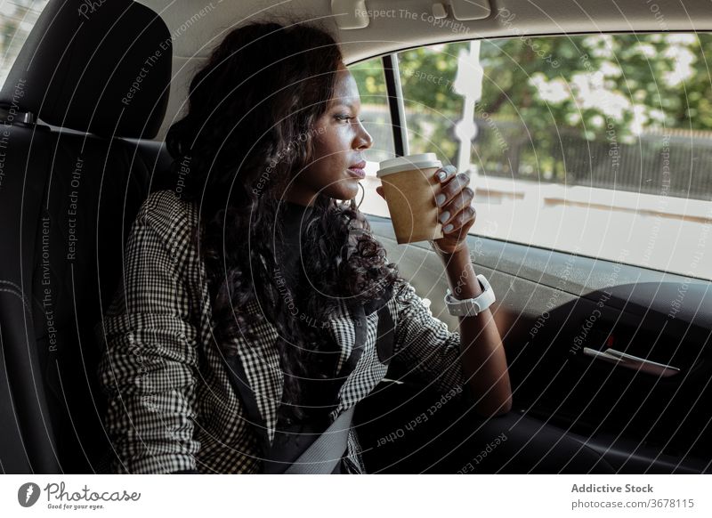 Nachdenkliche Geschäftsfrau mit Tasse Kaffee im Auto sitzend PKW trinken besinnlich Denken Frau beschäftigt modern ernst jung Afroamerikaner schwarz ethnisch