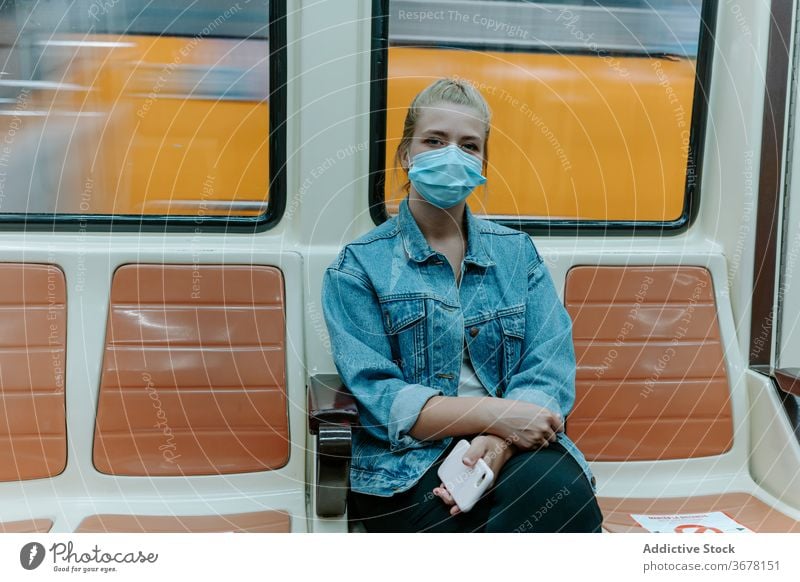 Junge Frau mit Schutzmaske im U-Bahn-Zug Coronavirus Passagier Mundschutz soziale Distanzierung COVID Pandemie Einschränkung Infektion Sitz allein unterirdisch