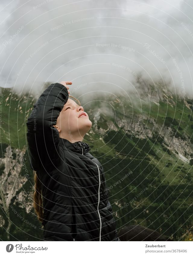 Kleines Mädchen schaut in die Wolken in den Alpen in Südtirol Kind beobachten Steppjacke klein schwarz Berge grün schauen Wandern Hand Profil Blick Weite Tal