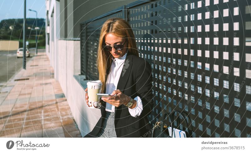 Geschäftsfrau benutzt Mobiltelefon und trinkt Kaffee Kaffee zum Mitnehmen Mode Straße Handy Texten Sonnenbrille Lifestyle Menschen professionell urban Tasse
