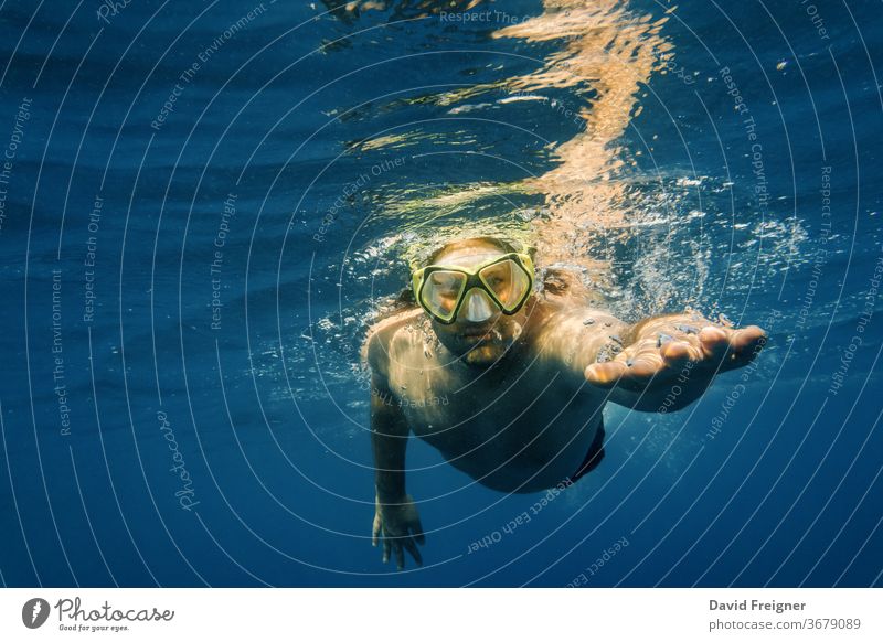 Männlicher Taucher im blauen Wasser. Offenes Meer, Ozean, Schwimmen, aktives Reisen und Unterwasser-Tauchkonzept. Sinkflug frei unter Wasser Mundschutz Mann