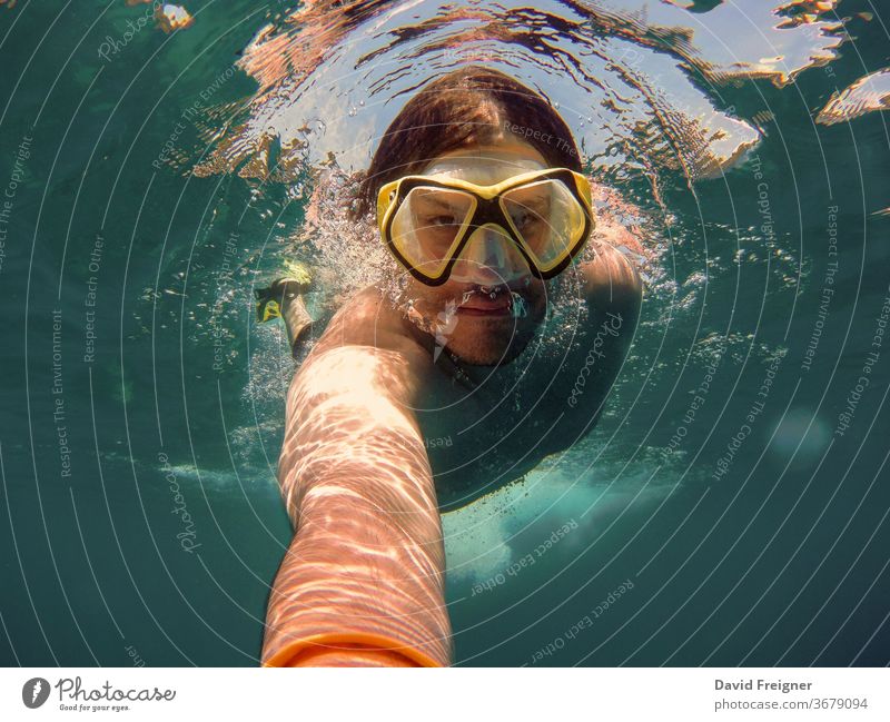Junger Mann mit Schnorchel und Tauchermaske schwimmt und nimmt ein Selfie unter Wasser. Konzept für Reisen, Urlaub und sportliche Aktivitäten. Meer jung MEER