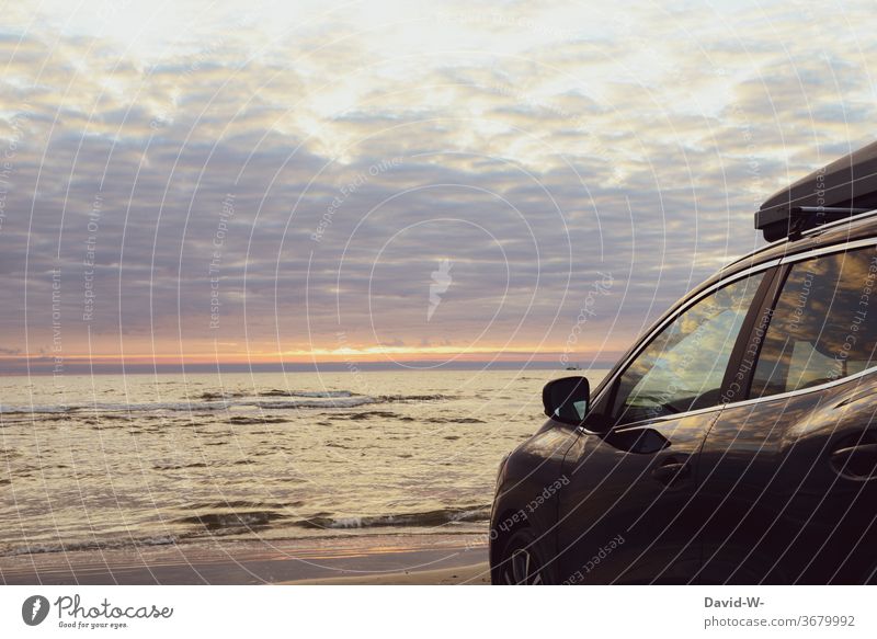 Autostrand - Auto mit Dachbox steht bei Sonnenuntergang am Meer Strand Urlauber Himmel Wasser Ozean Urlaubsstimmung parken Sonnenlicht wunderschön spiegelung