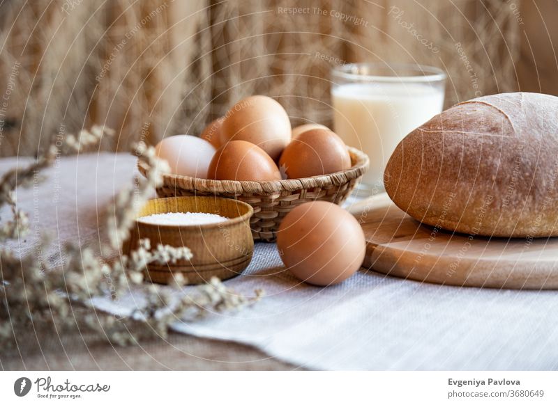 Frisches selbstgebackenes Brot, Milch, Eier und Salz auf Holztellern. Stilleben im rustikalen Stil Teigwaren Gebäck Amuse-Gueule Hintergrund Bäckerei Getränk