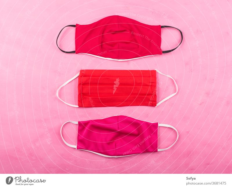 Rote Gesichtsmasken auf rosa Hintergrund. Coronavirus Mundschutz COVID19 Gewebe handgemacht soziale Distanzierung Schutz Mode Frau rot neue Normale Accessoire