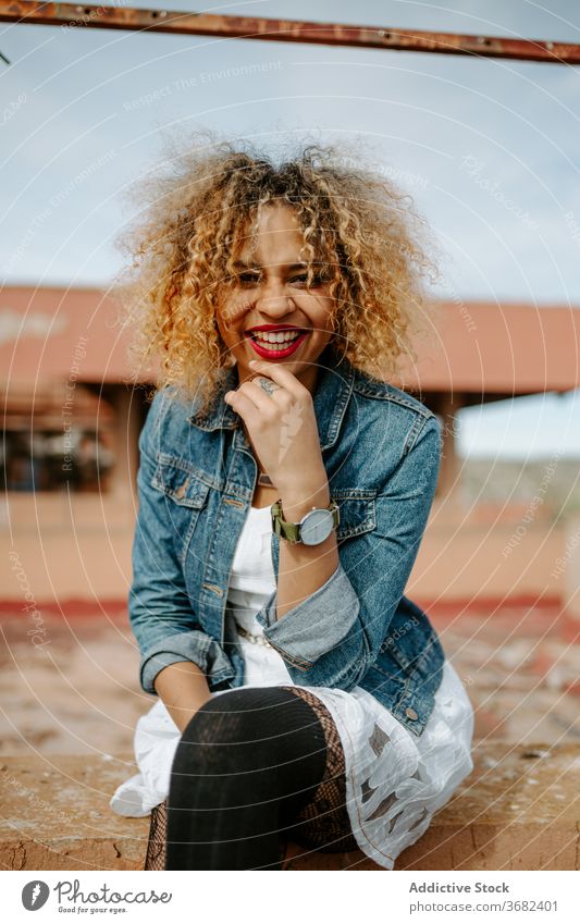 Stilvolle ethnische Frau auf alter Brücke Grunge trendy Mode schäbig Reling sitzen selbstbewusst Afroamerikaner schwarz charmant Lächeln Inhalt Windstille