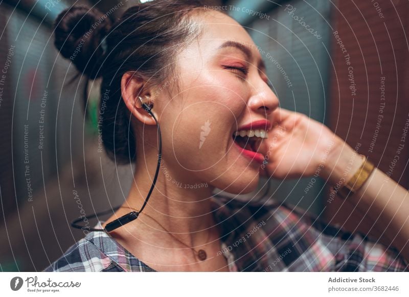 Frau mit Headset steht in einem unterirdischen Korridor Kommunizieren reden urban asiatisch ethnisch tausendjährig Freude Gespräch Lifestyle modern Spaß Gerät