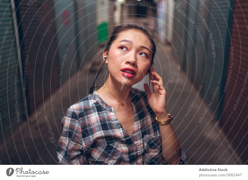 Frau mit Headset steht in einem unterirdischen Korridor Kommunizieren reden lässig urban asiatisch ethnisch tausendjährig Freude Gespräch Lifestyle modern Gerät