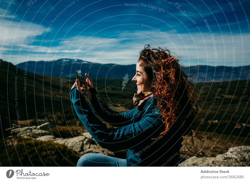 Positiver weiblicher Wanderer schießt Berge Frau Smartphone fotografieren Berge u. Gebirge Ausflug Landschaft Lächeln Kamm puerto de la morcuera Spanien wolkig