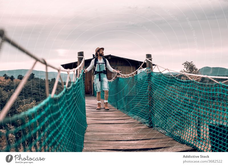 Reisender Mann zu Fuß entlang Holzsteg Suspension Steg Tourist Spaziergang Rucksack bewundern Landschaft hölzern Urlaub männlich Abenteuer Ausflug Tourismus