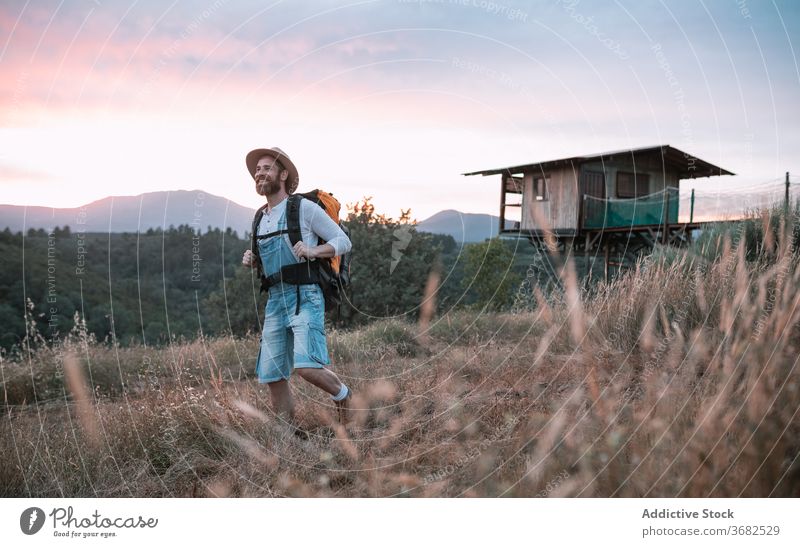 Glücklicher Mann in ländlicher Gegend Reisender Sonnenuntergang Berge u. Gebirge genießen Feld Rucksack Tourist Abend männlich malerisch Lächeln Fernweh Himmel