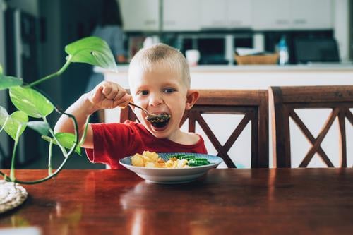 Süßes Kind, Vorschulkind, isst Gemüse zum Mittagessen im Speisesaal Kindheit Lebensmittel Glück Löffel veggies Mund Salatgurke Kartoffel hungrig Freude