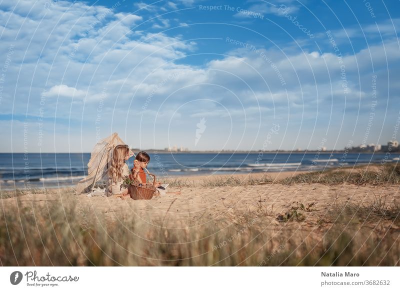 Zwei kleine Mädchen picknicken in einem kleinen Wigwam oder einer Hütte aus Zweigen am Sandstrand des australischen Ozeans Picknick Kind Glück Natur Sommer Tipi