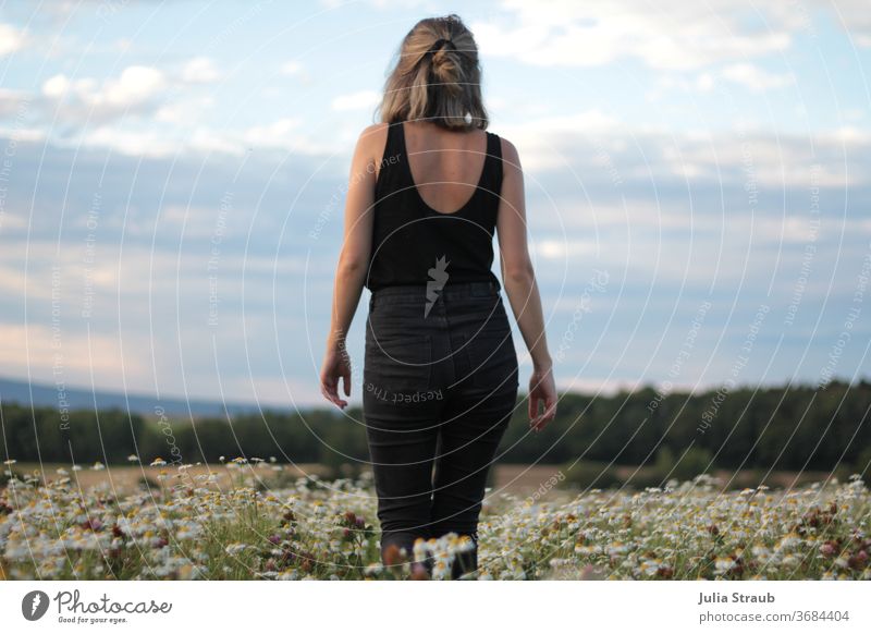 Junge Frau in Jeans läuft über ein Kamillenfeld mit herrlicher Aussicht Jeanshose schwarz Trauer Postkarte Wege & Pfade Himmel Wolken Horizont Landschaft Natur