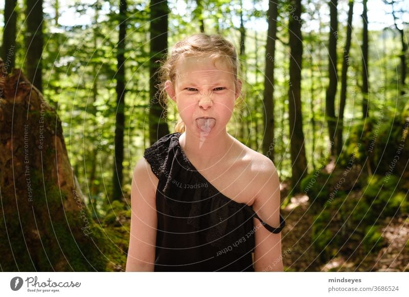 Wildes Mädchen im Wald streckt die Zunge raus wild Porträt Kind Kindheit Kindheitserinnerung Kindererziehung Spielen Außenaufnahme Freude