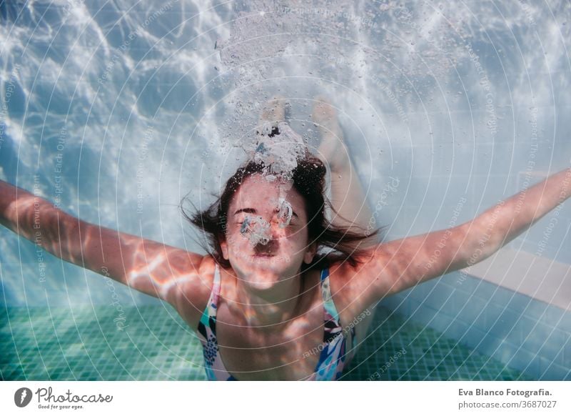 Porträt einer jungen Frau, die in einem Schwimmbad unter Wasser taucht. Sommer und lustiger Lebensstil abschließen Schwimmsport Blasen Spaß Kaukasier Pool