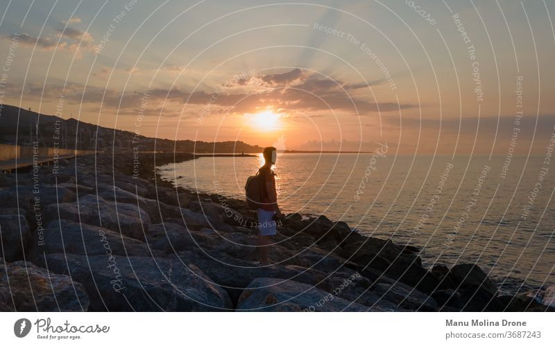 Junge bei Sonnenaufgang an einem Steg am Meer jung Person menschlich Strand Küste MEER Wasser Morgendämmerung Himmel gelb orange blau früh Tag mediterran Ruhe