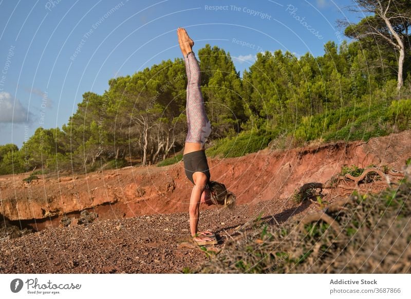 Frau in Strumpfhosen übt Handstand Yoga in der Mitte des Waldes natürlich vertikal Pose Invers Fitness Sport Stärke Gesundheit Mädchen Athlet Übung stark