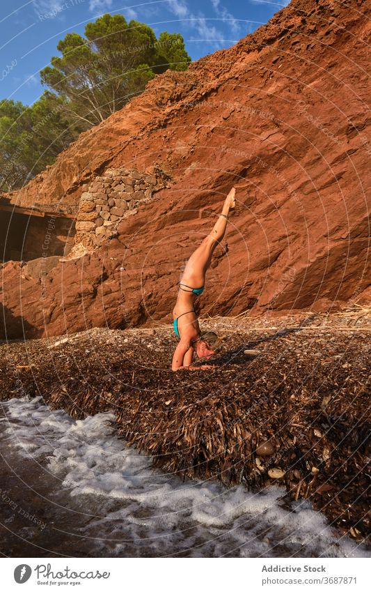 Frau macht eine Variation der Handstand-Yoga-Pose an einem Strand vertikal winken MEER Bewegung natürlich Wald Invers Fitness Sport Stärke Gesundheit Athlet