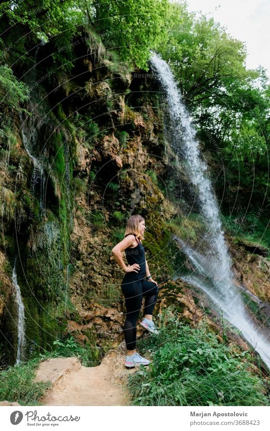 Junge Naturforscherin steht am Wasserfall Errungenschaft aktiv Erwachsener Abenteuer Ehrfurcht Kaskade Kaukasier Ausflugsziel genießend Genuss Umwelt Erkundung