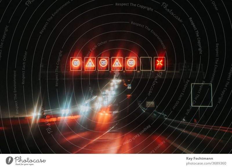 Reflexionen von Straßenschildern und Autos bei Nacht Asphalt Autobahn Unschärfe verschwommen PKW gefährlich dunkel Laufwerk fahren Fernstraße beleuchtet Reise