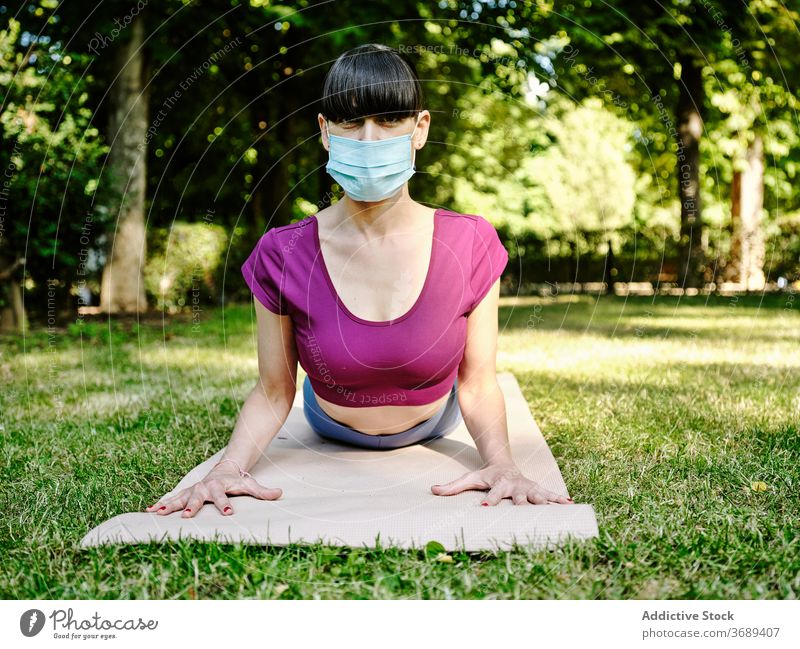 Frau macht Yoga in Cobra-Pose im Park Kobra-Pose Mundschutz Coronavirus ruhig beweglich sich[Akk] entspannen grün Harmonie Ausbruch Sommer Wellness Natur