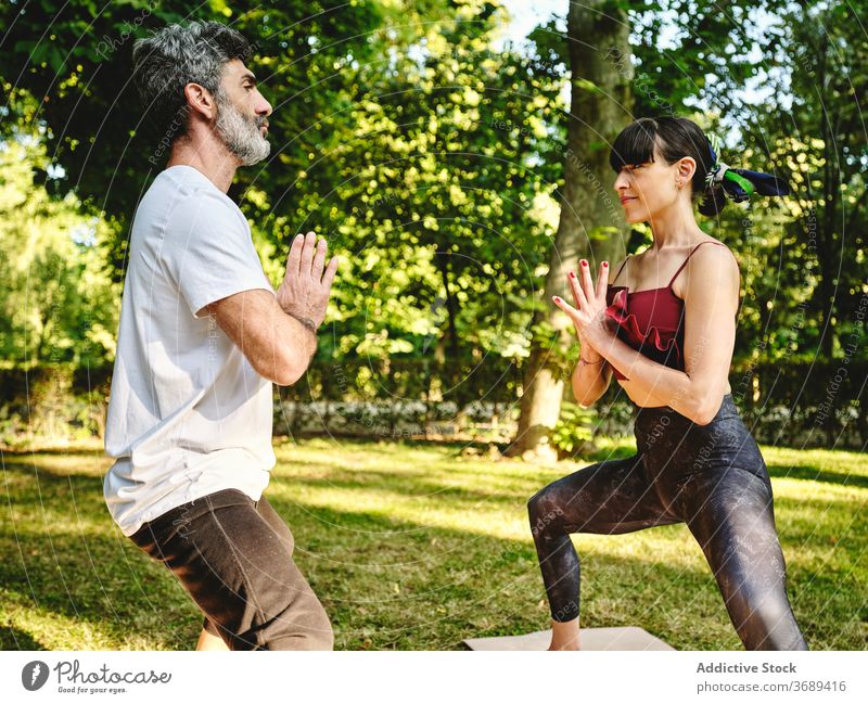 Mann und Frau üben Balance Yoga-Pose im Park Paar Asana Göttin Ukata Konasana Zusammensein Gleichgewicht stehen Wellness Lifestyle Harmonie Energie Vitalität
