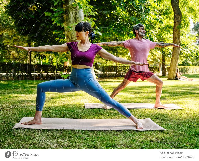Ruhiges Paar übt Yoga in Warrior Pose zusammen Krieger-Pose Zusammensein Park Barfuß sonnig virabhadrasana Training Partnerschaft ruhig Gesundheit Gelassenheit