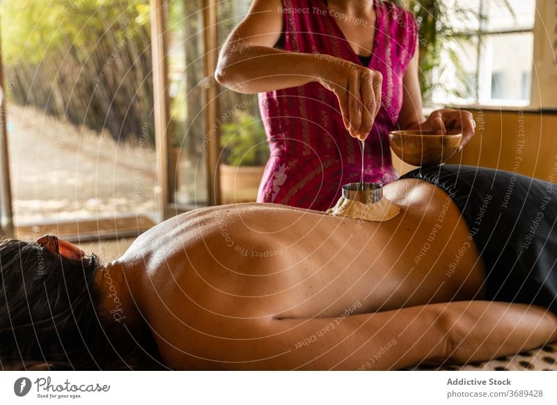 Anonyme Frau bekommt ayurvedische Behandlung auf dem Rücken ayurveda Erdöl heilen eingießen Massage bewerben Leckerbissen Therapie Verfahren Pflege