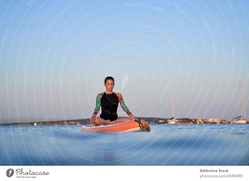Flexible Frau macht Yoga in Lotus-Pose auf Paddleboard Sonnenuntergang Surfer Paddelbrett Gleichgewicht MEER Wasser Gesundheit Natur Harmonie