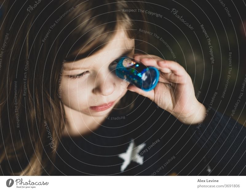 Kind schaut durch ein Spielzeug-Kaleidoskop Mädchen Blick Spielen jung spielerisch Wissenschaft Lernen