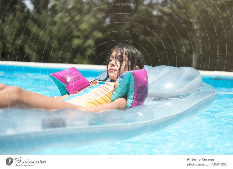 entspanntes kleines Mädchen mit Muffs auf aufblasbarer Matte oberirdisches Schwimmbecken vor Hinterhof Windstille Kaukasier Kind Kindheit Schwimmer Schutzbrille