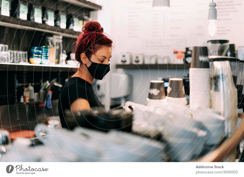 Weibliche Barista bereitet Kaffee im Café zu vorbereiten Frau Mundschutz Coronavirus Kaffeemaschine Abfertigungsschalter lecker Maschine behüten verhindern