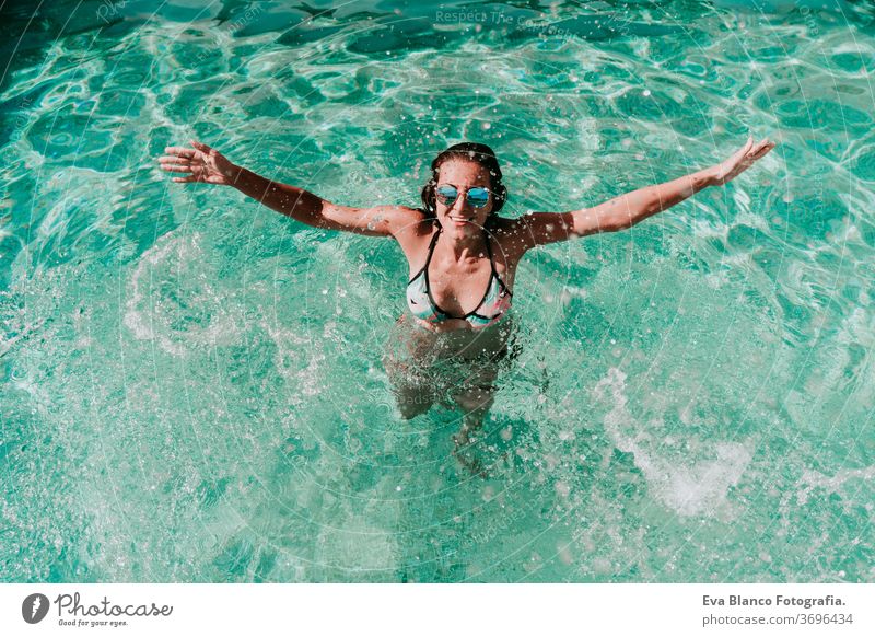 glückliche Frau am Pool, die Spaß daran hat, Wasser zu spritzen. Sommer und Lebensstil eine Glück Schwimmbad Sonnenbrille platschen Geplätscher Blauwasser heiß