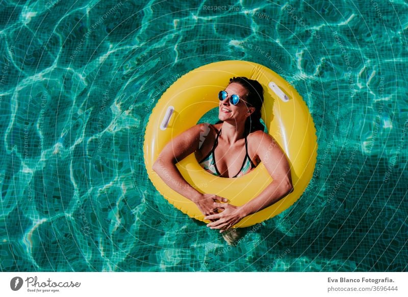 Draufsicht auf eine glückliche junge Frau, die in einem Pool in einem gelben Donut schwimmt. Sommer und lustiger Lebensstil gelbe Donuts aufblasbar Schwimmsport