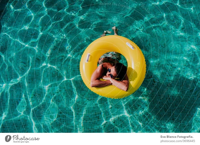 Draufsicht auf eine glückliche junge Frau, die in einem Pool in einem gelben Donut schwimmt. Sommer und lustiger Lebensstil gelbe Donuts aufblasbar Schwimmsport