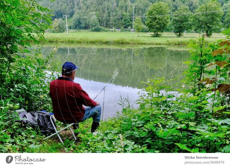 Angler sitzt am Flussufer im Grünen Angeln Wasser Fischer Ansitzen Ufer Gebüsch Wald grün Erholung Stille Ruhe Fische fangen Freizeit & Hobby Natur warten