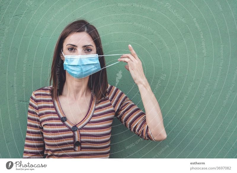 Frau mit medizinischer Maske, die eine medizinische Schutzmaske hält Coronavirus Junge Frau Virus Seuche Pandemie Quarantäne covid-19 Symptom Medizin Gesundheit