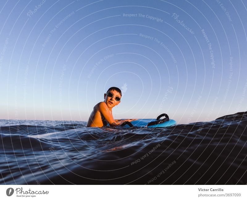 Ein kleiner Junge lernt an einem sonnigen Sommertag draußen an der Küste im Bodyboard bodyboarder Kind Feiertag Urlaub Freizeit Ufer Lifestyle Surfbrett
